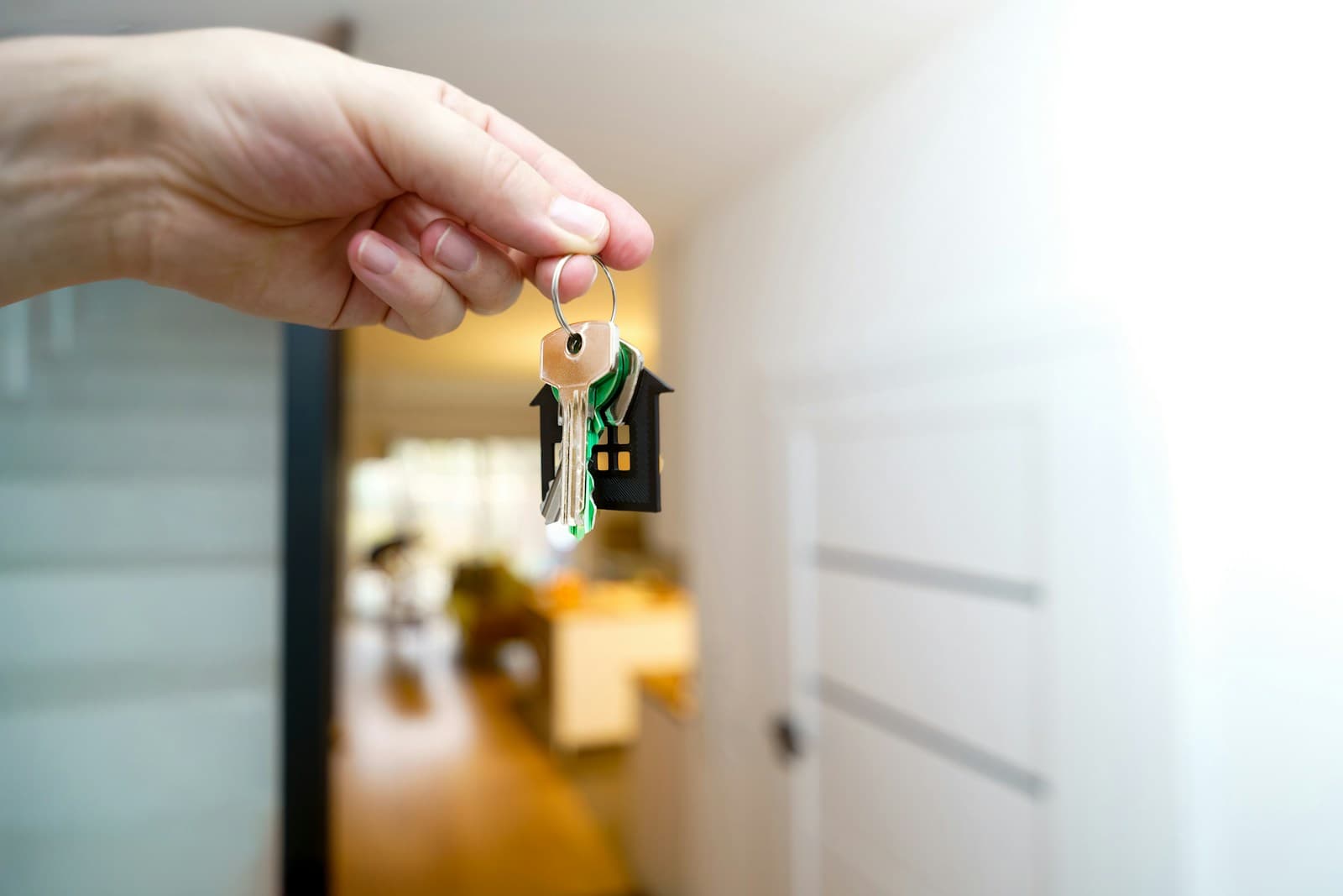 Una mà sostenint les claus d’una casa davant la porta