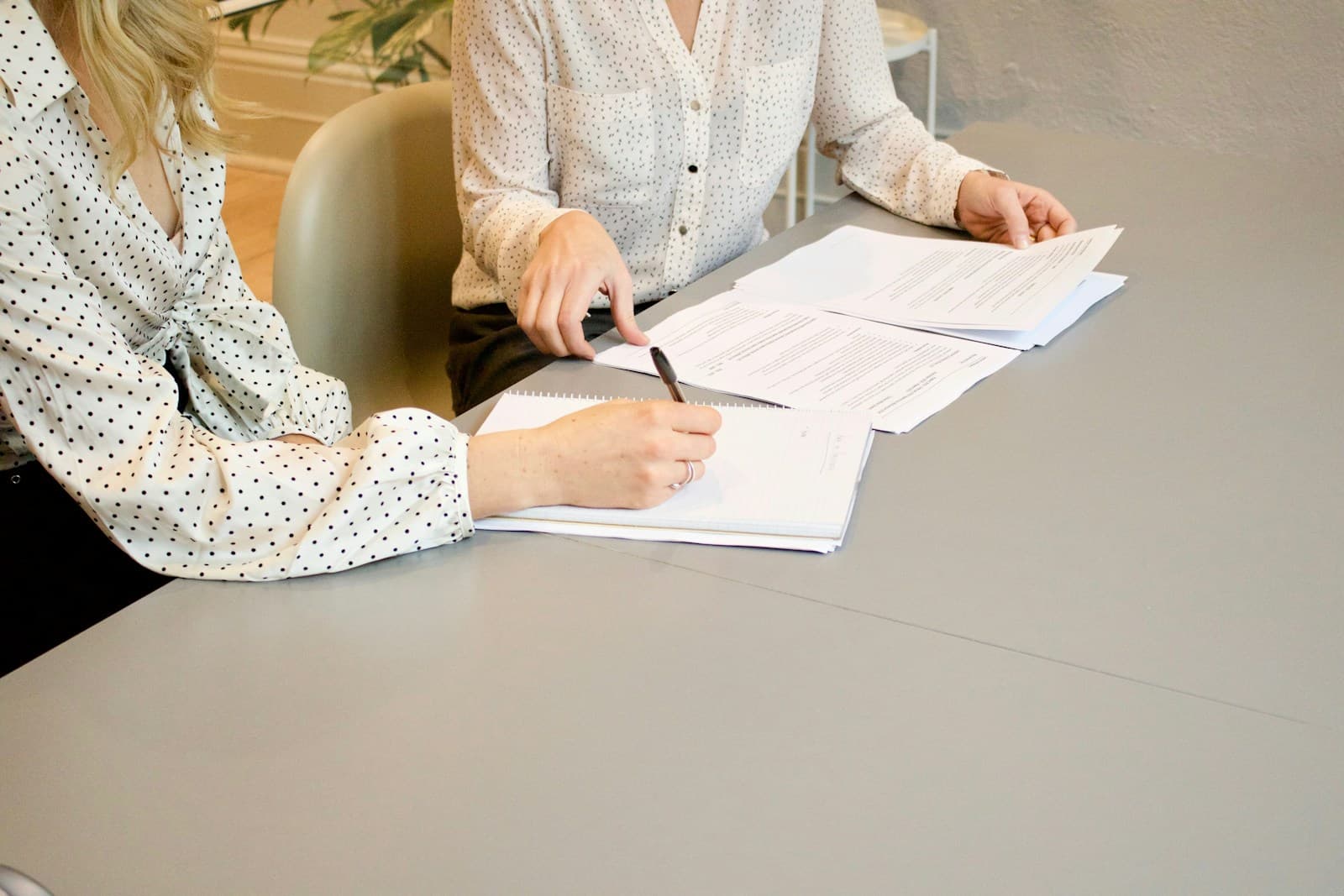 Una dona signant documents amb una altra persona al costat